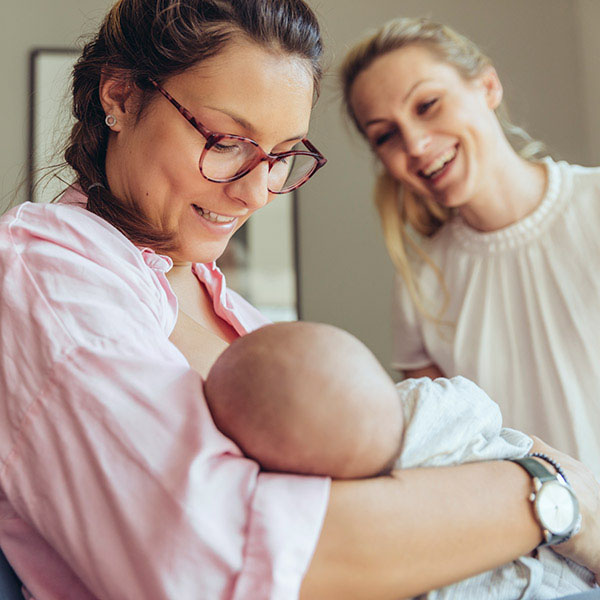 Two women smiling at newborn
